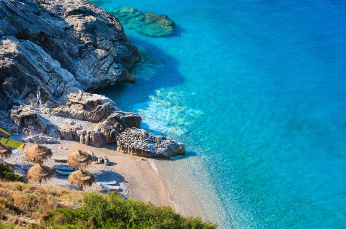 Clear turquoise water beside an Albanian coastal cove